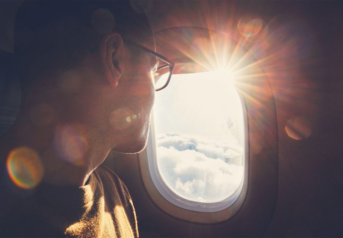 Man looking out the window of an airplane in flight